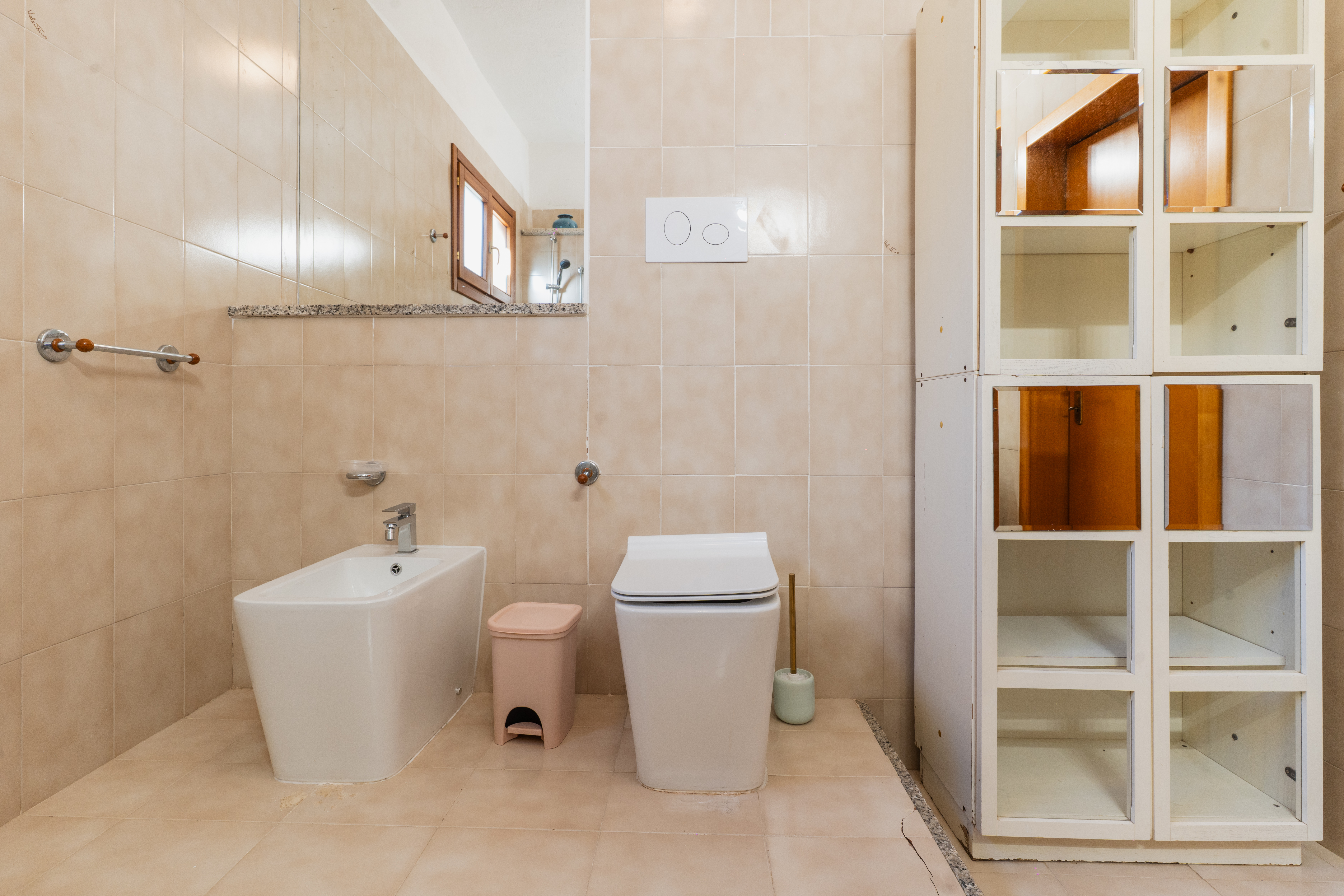 Primo bagno completo con finiture beige e mobiletto
